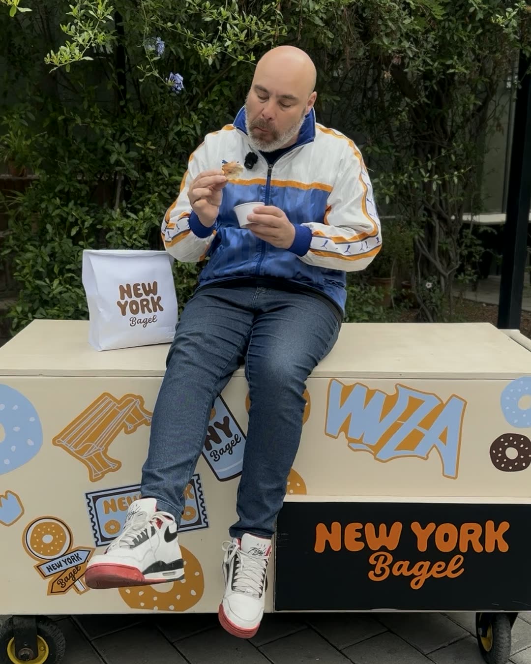 Persona probando un bagel junto a una bolsa New York Bagel